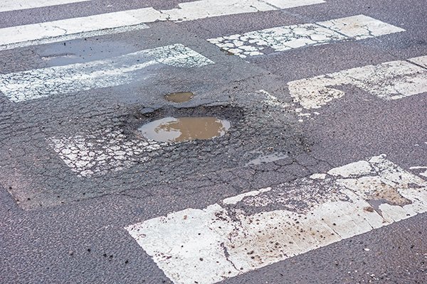 Large pothole on the road, on pedestrian crossing